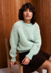 Naomi mesure 1m70 et porte le pull en taille 2 et la jupe en XS.