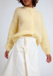 Naomi mesure 1m70 et porte le cardigan en taille 2 et la jupe en XS/S.