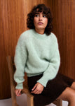 Naomi mesure 1m70 et porte le pull en taille 2 et la jupe en XS.